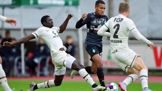 St. Paulis Afeez Aremu (l.) und Sebastian Ohlsson (r.) versuchen, Bremens Felix Agu vom Ball zu trennen. © Witters 
