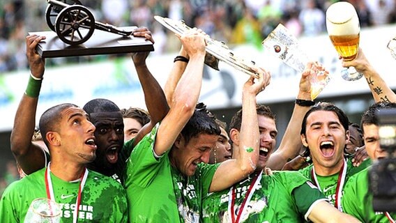 Die Wolfsburger Spieler feiern feuchtfröhlich.. © dpa 