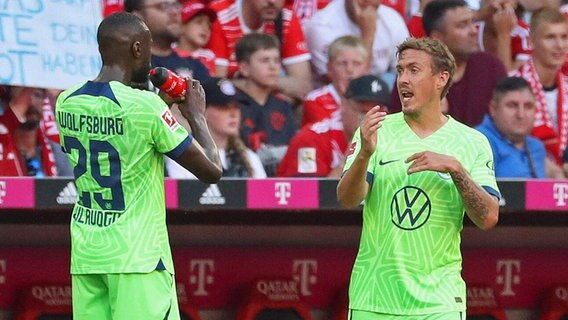 Die Wolfsburger Profis Josuha Guilavogui (l.) und Max Kruse diskutieren während einer Trinkpause miteinander. © IMAGO / regio24 