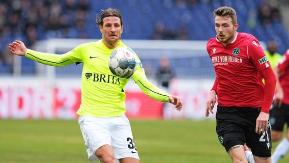 Hannovers Jannes Horn (r.) und Wiesbadens Stefan Aigner kämpfen um den Ball. © picture alliance/dpa Foto: picture alliance/Peter Steffen/dpa