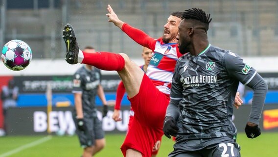 Hannovers Kingsley Schindler (r.) und Heidenheims Norman Theuerkauf kämpfen um den Ball. © dpa-Bildfunk Foto: Stefan Puchner/dpa