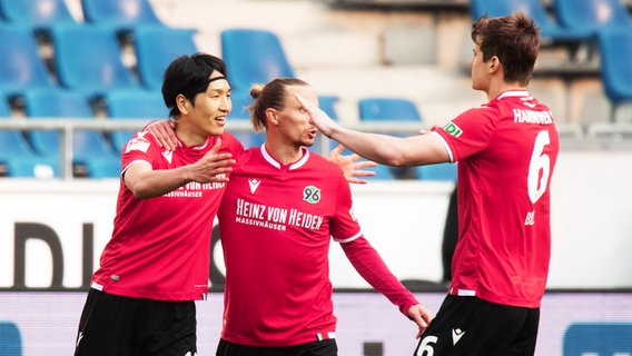 Genki Haraguchi bejubelt seinen Treffer zum 1:0 mit Hannovers Niklas Hult und Jaka Bijol. © picture alliance/dpa Foto: Julian Stratenschulte