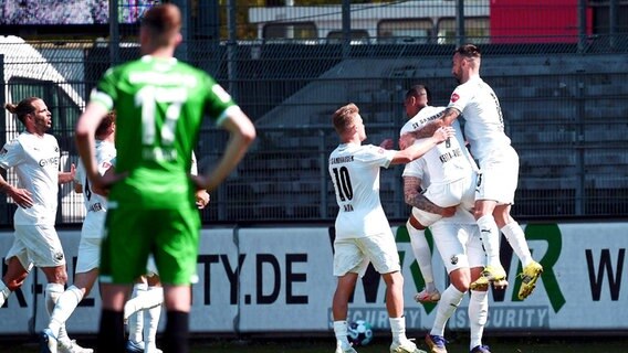 Jubelnde Sandhausener vor einem enttäuschten Hannover Spieler. © IMAGO / Jan Huebner Foto: Jan Huebner