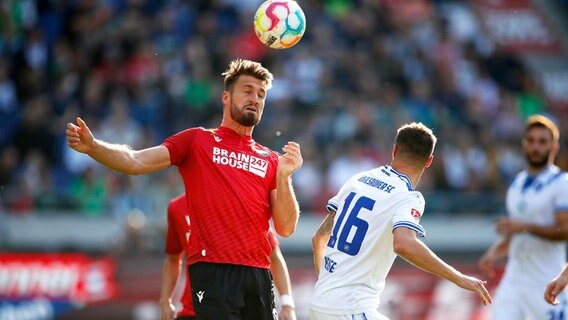 Hannovers Hendrik Weydandt (l.) und Karlsruhes Philip Heise kämpfen um den Ball. © IMAGO / Joachim Sielski 