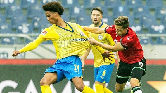 Braunschweigs Sidi Sané (l.) und Hannovers Fabian Kunze kämpfen um den Ball. © picture alliance/dpa | Axel Heimken 