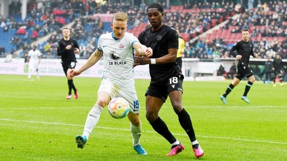 Rostocks Kai Pröger (l.) und Hannovers Derrick Köhn kämpfen um den Ball. © IMAGO / osnapix 