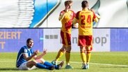 Rostocks Damian Roßbach (l.) ist enttäuscht, während Karlsruhes Spieler einen Treffer bejubeln. © IMAGO / Ostseephoto 