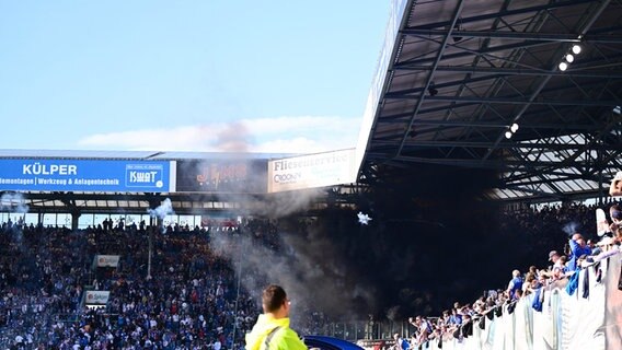 Rostock-Fans werfen Rauchbomben und Raketen auf das Spielfeld und sorgen ob der Rauchschwaden für eine Spielunterbrechung. © Witters/LeonieHorky 