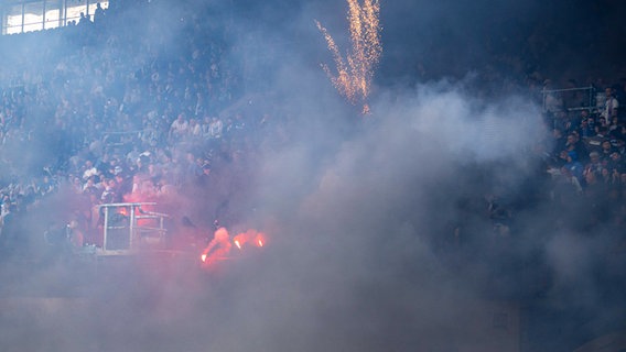 Rostock-Fans werfen Rauchbomben und Raketen auf das Spielfeld und sorgen ob der Rauchschwaden für eine Spielunterbrechung. © IMAGO / Fotostand 
