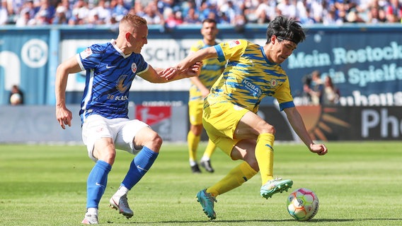 Braunschweigs Keita Endo (r.) und Rostocks Kai Pröger kämpfen um den Ball. © IMAGO / Jan Huebner 