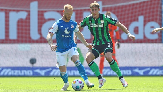 Rostocks Nils Fröling (l.) und Hannovers Phil Neumann kämpfen um den Ball. © IMAGO / Jan Huebner 