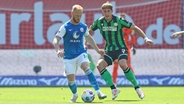 Rostocks Nils Fröling (l.) und Hannovers Phil Neumann kämpfen um den Ball. © IMAGO / Jan Huebner 