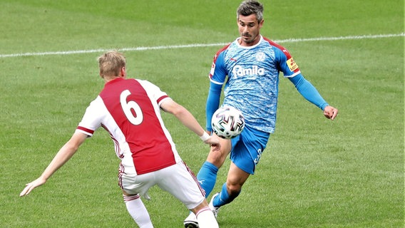 Holstein Kiels Fin Bartels (r.) legt im Testspiel gegen Ajax Amsterdam den Ball an Gegenspieler Kenneth Taylor vorbei. © imago images/Holsteinoffice Foto: Patrick Nawe