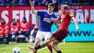 Kiels Philipp Sander (l.) und Kaiserslauterns Tymoteusz Puchacz kämpfen um den Ball. © IMAGO / Eibner 