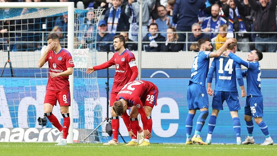 Die HSV-Akteure László Bénes, Jonas Meffert und Miro Muheim (v.l.) sind enttäuscht, während Karlsruhes Spieler einen Treffer bejubeln. © WITTERS/JoergHalisch 