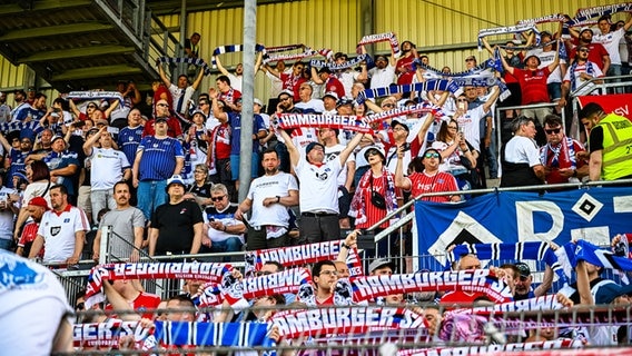 Die mitgereisten HSV-Fans halten vor dem Spiel gegen den SV Sandhausen ihre Schals in die Höhe. © IMAGO / Lobeca 