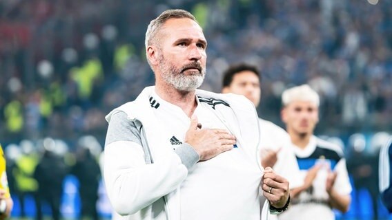 HSV-Trainer Tim Walter bedankt sich bei den Fans und fasst sich mit der Hand auf das HSV-Wappen. © IMAGO / Jan Huebner 