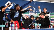 HSV-Trainer Merlin Polzin (r.) wird auf der Pressekonferenz nach dem Aufstieg von seinen Spielern mit einer "Bierdusche" überrascht. © Witters/LeonieHorky 