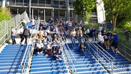 HSV-Fans sitzen auf einer Treppe um den Frauen des Hamburger SV beim Spiel gegen den SC Freiburg II zuzuschauen. © NDR Foto: Florian Neuhauss