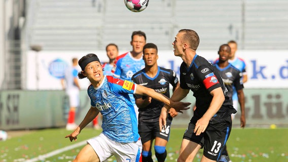 Kiels Jae-sung Lee (l.) und Paderborns Sebastian Schonlau kämpfen um den Ball. © imago images / Claus Bergmann 