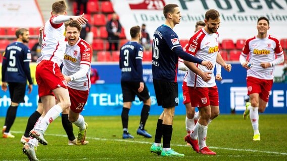 Kiels Spieler sind enttäuscht, während Regensburgs Spieler einen Treffer bejubeln. © IMAGO / Sascha Janne 