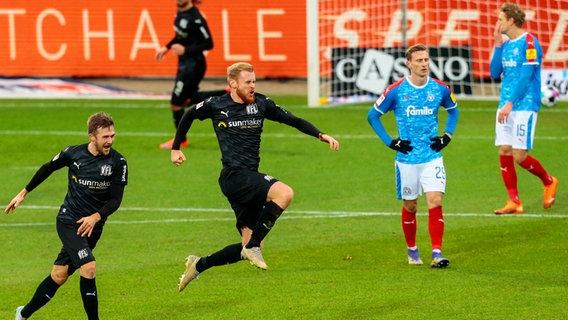 Osnabrücks Sebastian Kerk (2.v.l.) bejubelt seinen Treffer, während Kiels Spieler enttäuscht sind. © imago images / Jan Huebner 