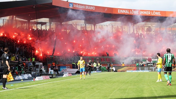 Anhänger von Eintracht Braunschweig zünden Pyrotechnik.  © IMAGO / regios24 