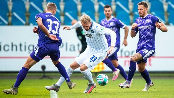 Osnabrücks Timo Beermann, Karlsruhes Philipp Hofmann und Osnabrücks Maurice Trapp kämpfen um den Ball. © picture alliance/dpa Foto: David Inderlied