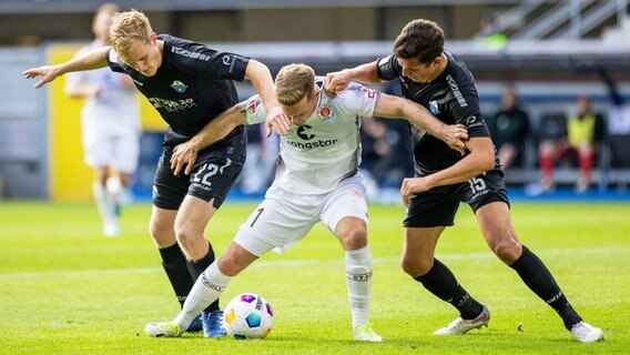 St. Paulis Johannes Eggestein (M.) kämpft gegen Paderborns Mattes Hansen (l.) und Tobias Müller um den Ball. © IMAGO / Moritz Müller 
