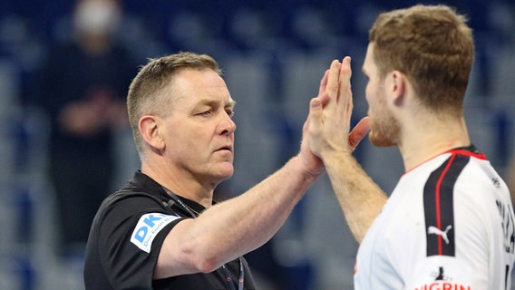 Bundestrainer Alfred Gislason (l.) klatscht mit Handball-Nationalspieler Johannes Golla ab. © IMAGO / Kessler-Sportfotografie 