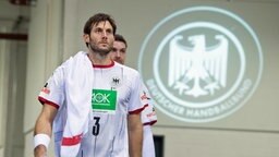 Uwe Gensheimer, Kapitän der deutschen Handball-Nationalmannschaft, neben dem Logo des Deutschen Handballbundes. Im Hintergrund Hendrik Pekeler.