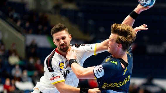 Der deutsche Handball-Spieler Fabian Wiede (l.) und Schwedens Jonathan Carlsbogard kämpfen um den Ball. © imago images/Bildbyran 