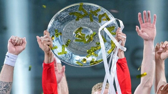 Hände recken die Handball-Meisterschale empor. © IMAGO / foto2press 