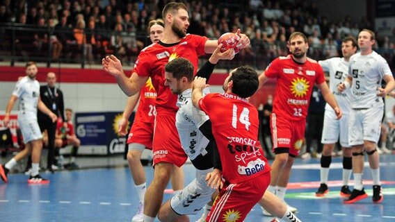 Hendrik Pekeler vom THW Kiel (2.v.l.) wird von Yannick Dräger (l.) und Peter Strosack von TuS N-Lübbecke am Abschluss gehindert. © IMAGO / osnapix 