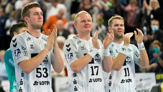 Die Kieler Handballer Nikola Bilyk, Patricvk Wiencek und Petter Oeverby (v.l.) applaudieren den THW-Fans. © IMAGO / Eibner 