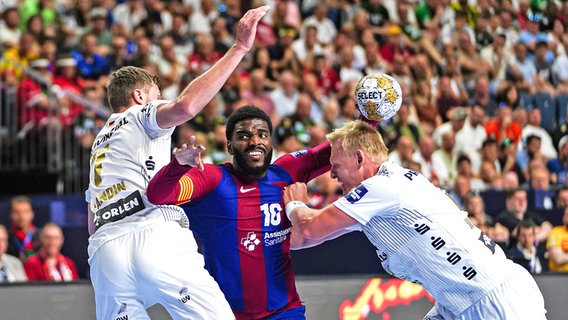 Magnus Landin (l.) und Patrick Wiencek (r.) vom THW Kiel im Duell mit Dika Mem vom FC Barcelona © picture alliance / Eibner-Pressefoto | Eibner Pressefoto/Marcel von Fehrn 