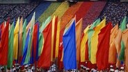 Abschlussfeier im Olympiastadion, das olympische Feuer im Hintergrund, Sportler mit bunten Fahnen im Vordergrund © ullstein bild - Schlage 