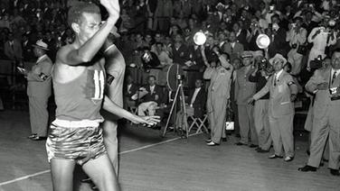 Der äthiopische Marathonläufer Bikila Abebe winkt, während er als Sieger des Marathonlaufs der Olympischen Spiele in Rom mit einer Zeit von 2:15:16 Stunden barfuß ins Ziel läuft. © ullstein bild - UPI
