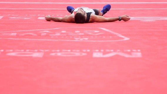 Ein Marathonläufer in Hamburg liegt im Ziel flach auf dem Boden. © Witters 