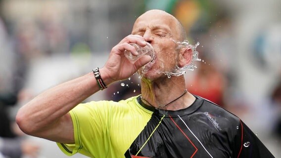 Ein Marathonläufer trinkt Wasser. © Witters 