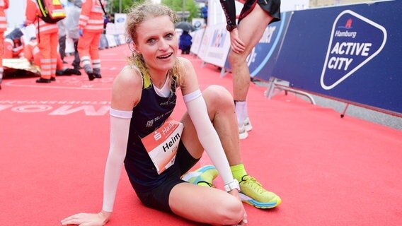 Thea Heim sitzt im Ziel des Hamburg-Marathons auf dem Boden. © Witters 