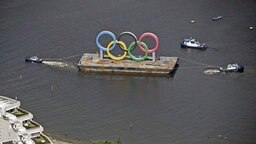 Die Olympischen Ringe werden in der Bucht von Tokio von Schleppern gezogen. © imago images/Kyodo News 
