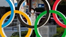Eine Frau in Tokio schaut durch die Olympischen Ringe © IMAGO / ZUMA Wire 