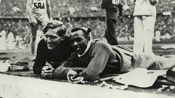 Der Deutsche Luz Long und der Amerikaner Jesse Owens beobachten ihre Konkurrenten beim Weitsprung. © picture-alliance / akg-images