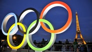 Die olympischen Ringe vor dem Eiffelturm in Paris bei Nacht. © abaca Foto: Apaydin Alain/ABACA