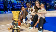 Basketball-Profi Dennis Schröder (3.v.l.) mit seiner Familie und dem WM-Pokal. © IMAGO / camera4+ 