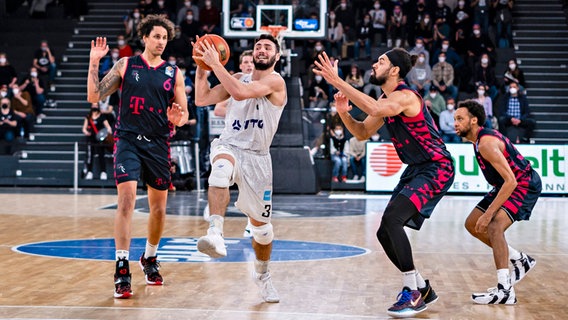 Hamburgs Basketballprofi Max DiLeo (2.v.l.) setzt sich gegen die Bonner Michael Kessens (l.) und Jeremy Morgan durch. © IMAGO / Baering 