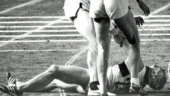 Der estnische Sportler Rein Aun und Horst Beyer bemühen sich um den nach dem Zieleinlauf des 1500m-Laufes vor Erschöpfung gestürzten Willi Holdorf © picture-alliance / dpa 