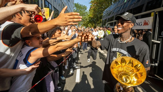 Dennis Schröder mit dem WM-Pokal und Fans © IMAGO / camera4+ 