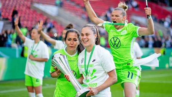 Anna Blässe und Ewa Pajor (v.l.) vom VfL Wolfsburg halten den DFB-Pokal in den Händen, dahinter jubel Alexandra Popp © IMAGO / Eibner 